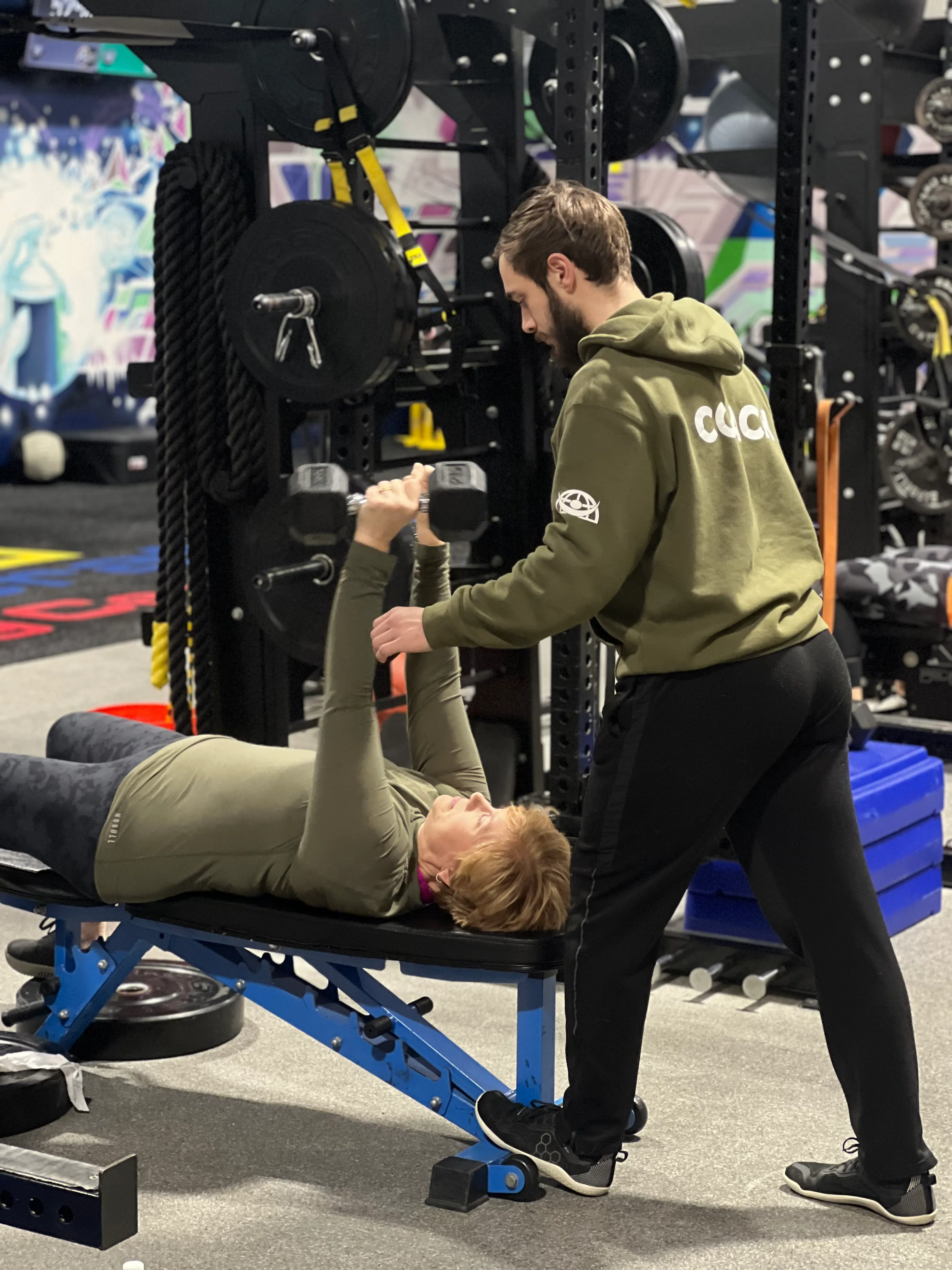 Personal trainer coaching a member on the bench press at Next Gen