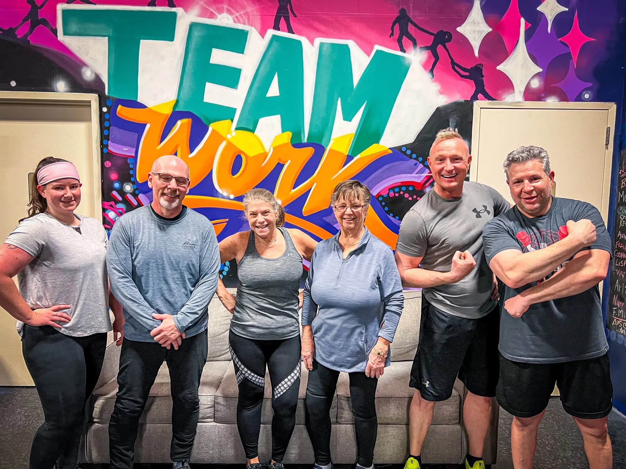 Next Gen team flexing in front of TEAM WORK mural